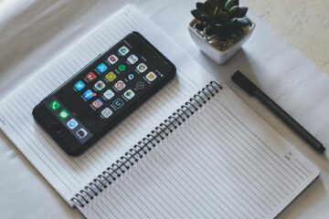 Flat lay featuring a smartphone on a spiral notebook beside a succulent plant and pen. (Photo by Jonathan Robles on Pexels)