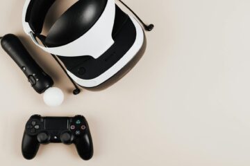 High-angle view of gaming controllers and VR headset on beige surface, showcasing modern technology. (Photo by www.kaboompics.com on Pexels)