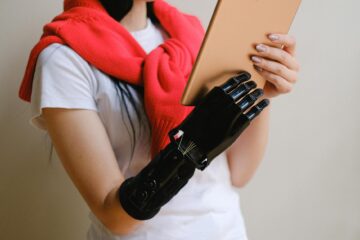 A person with a bionic hand holding a tablet, showcasing advanced prosthetic technology. (Photo by Anna Shvets on Pexels)