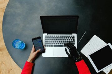 A person using a laptop, smartphone, and tablet with a prosthetic hand, emphasizing digital conne... (Photo by Anna Shvets on Pexels)
