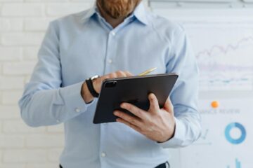 Businessman using a tablet for data analysis in a modern office. (Photo by www.kaboompics.com on Pexels)