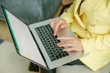 A person in a yellow jacket typing on a laptop indoors. Perfect for depicting work from home or b... (Photo by Yaroslav Shuraev on Pexels)